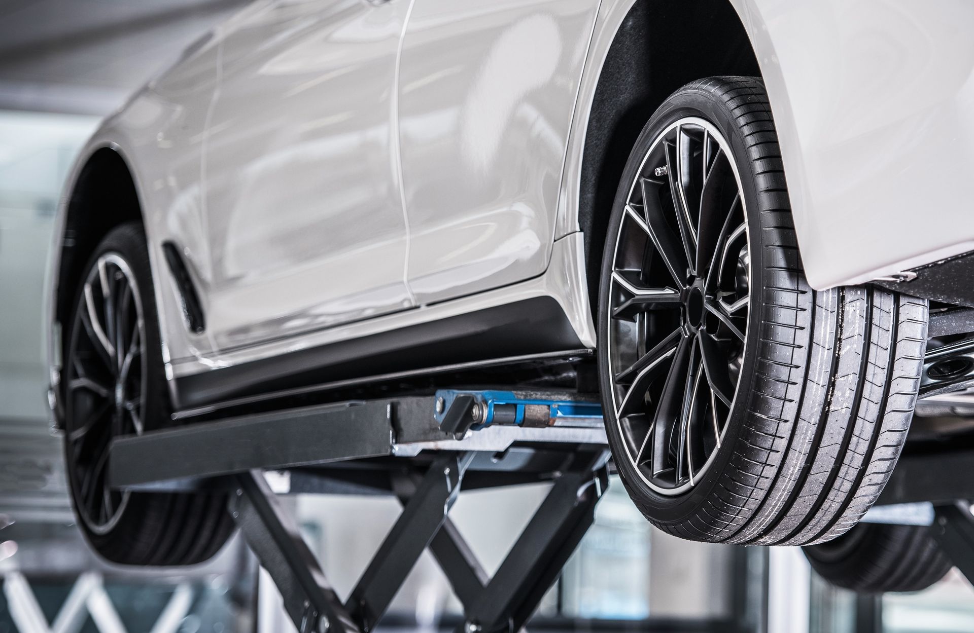 Silver car on a hydraulic lift in an auto repair shop, viewed from below