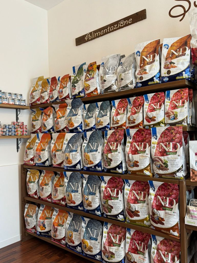 Scaffali pieni di sacchetti colorati di cibo per animali domestici in un corridoio di un negozio di animali.