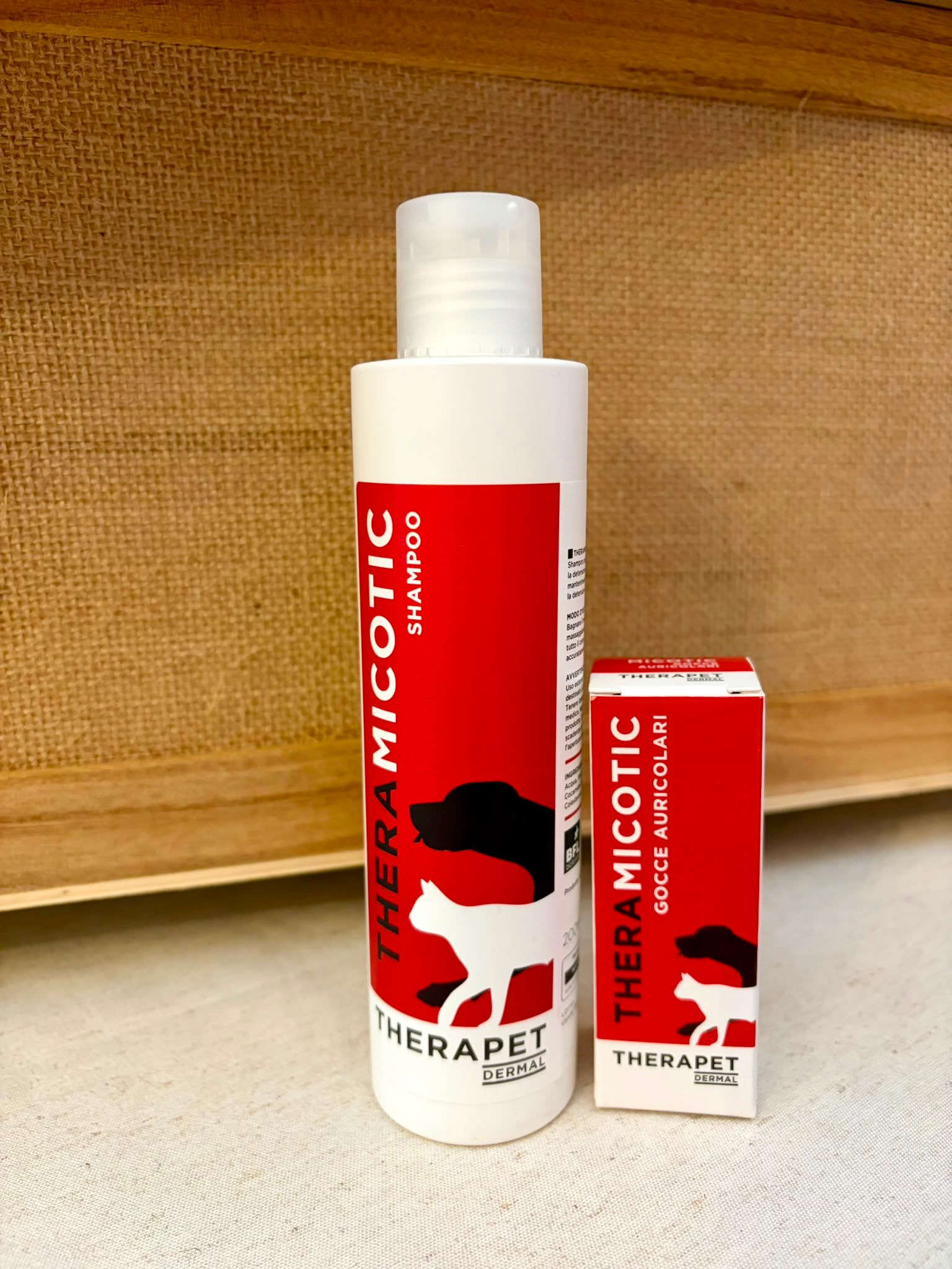 Flaconi Theramicotic bianchi e rossi su una superficie intrecciata su sfondo beige.
