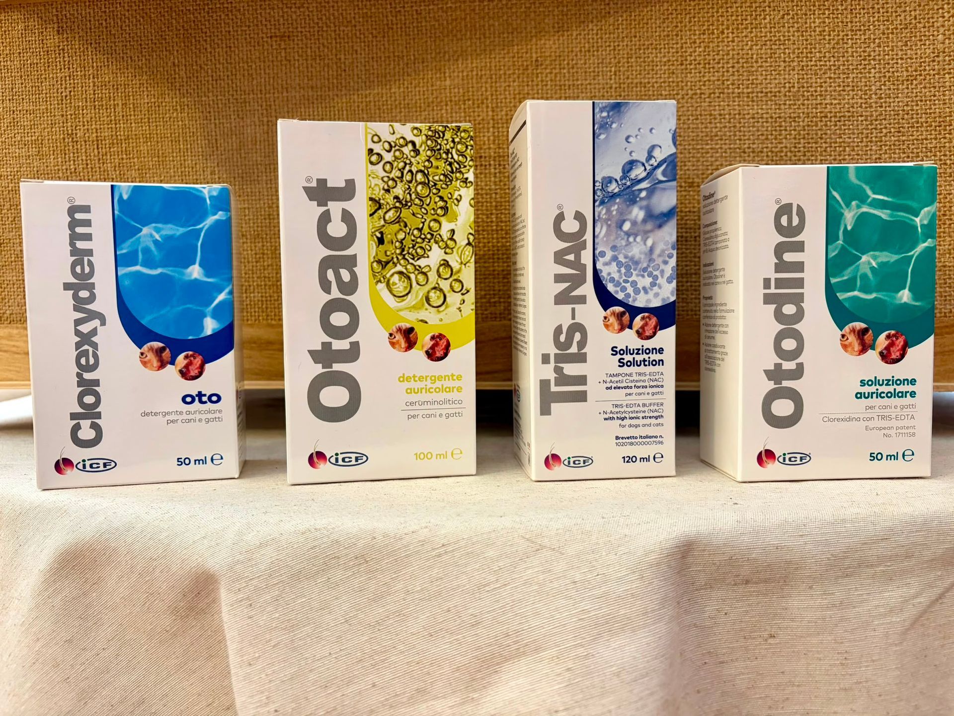 Quattro scatole di medicinali allineate su un telo bianco, con confezioni blu e verdi.