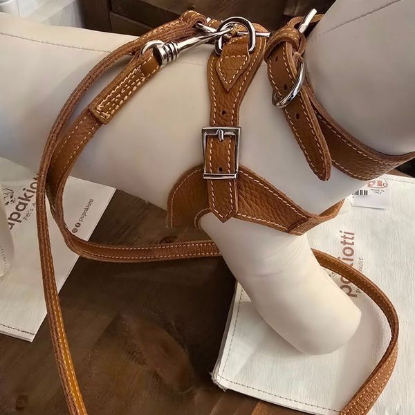 Cinghie di imbracatura in pelle marrone con fibbie argentate avvolte attorno alla gamba di un manichino bianco.