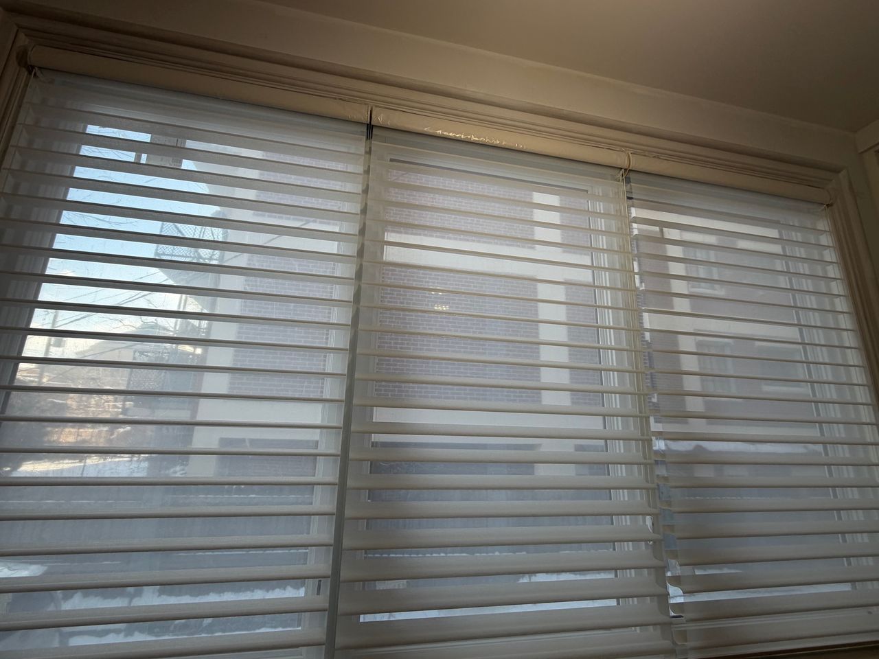 White window blinds filtering daylight in a room