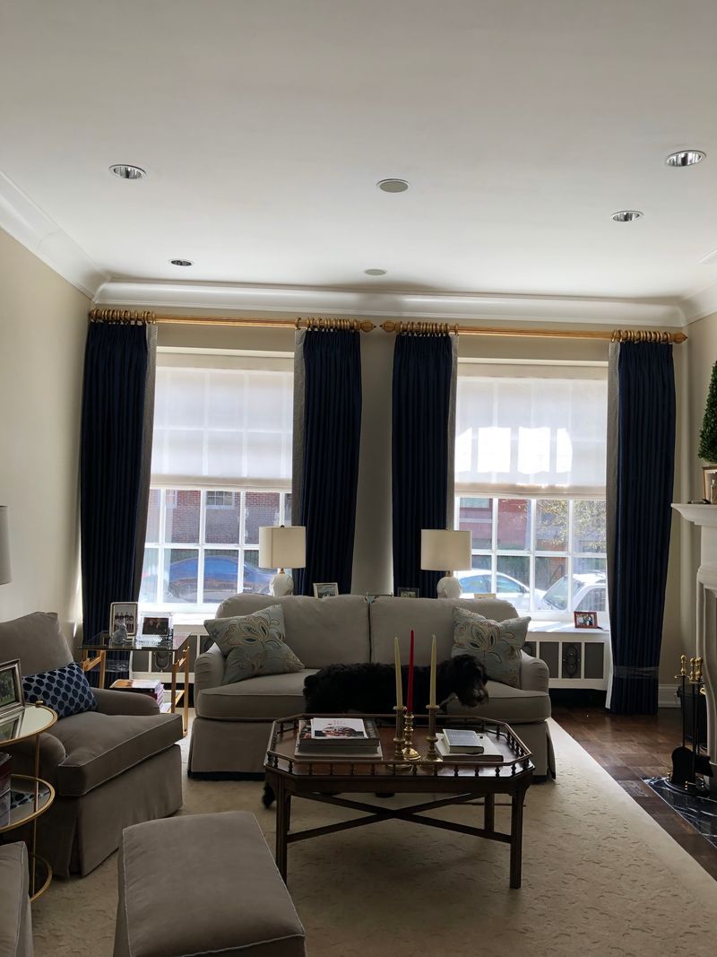 Bright living room with blue curtains, white sofa, coffee table, and large windows