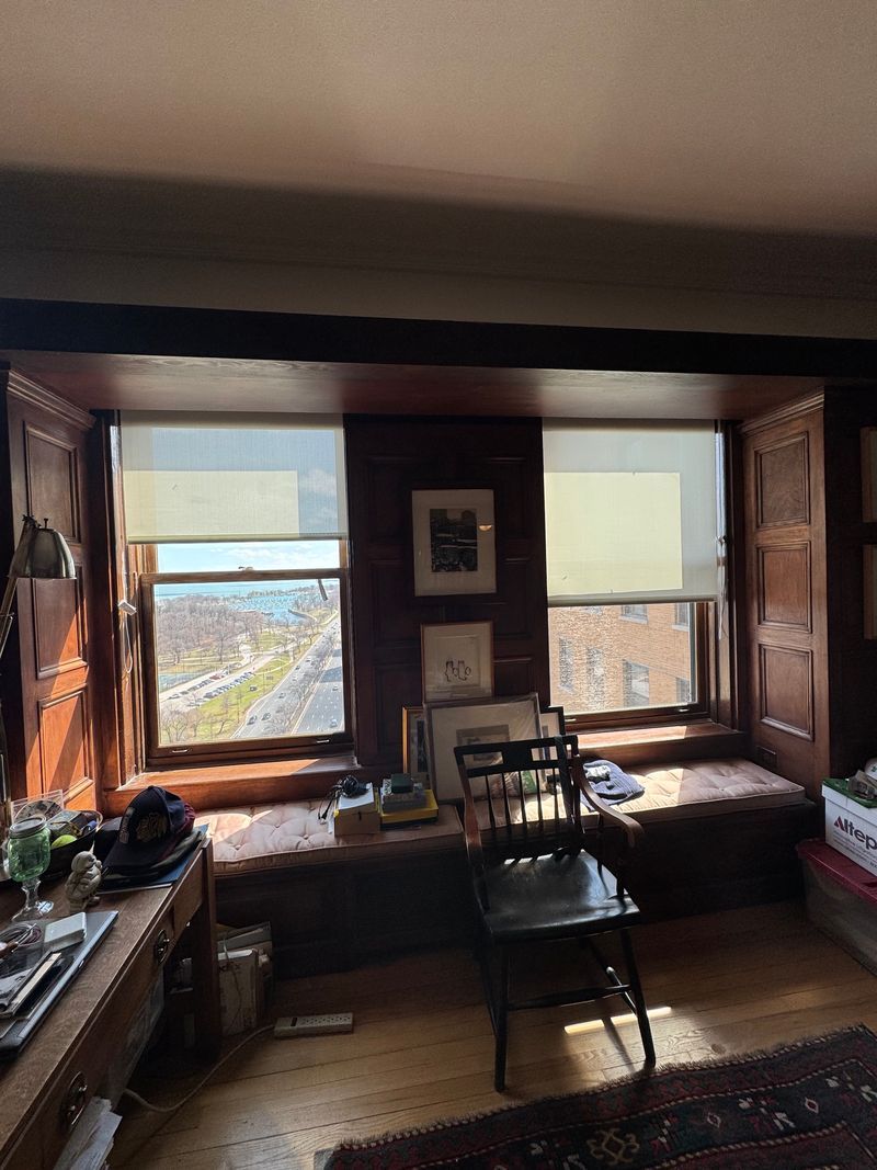 Cozy window seat in a room with open shutters, a table, and a city view outside.