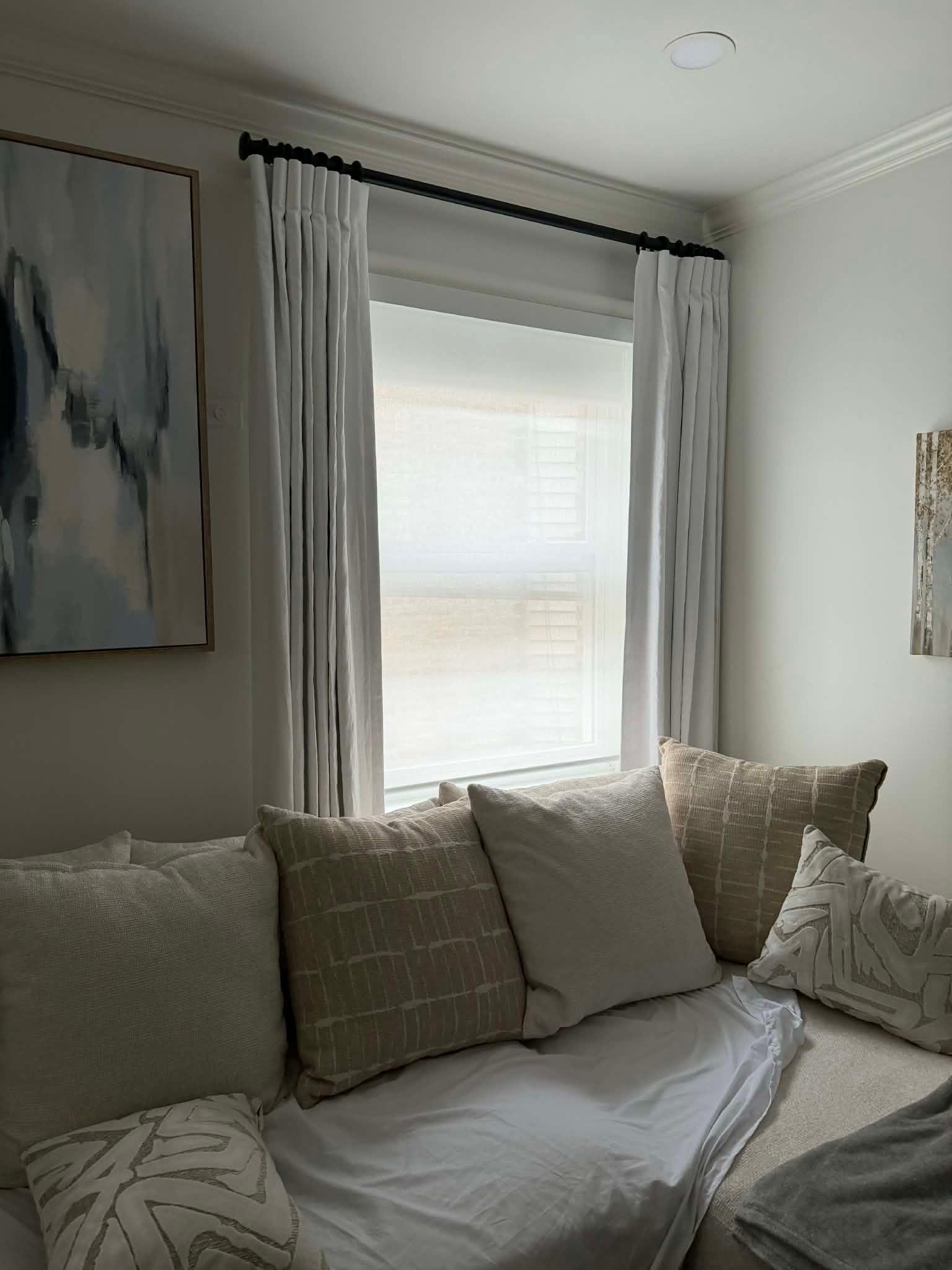 Cozy living room corner with light gray sofa, white curtains, and a bright window