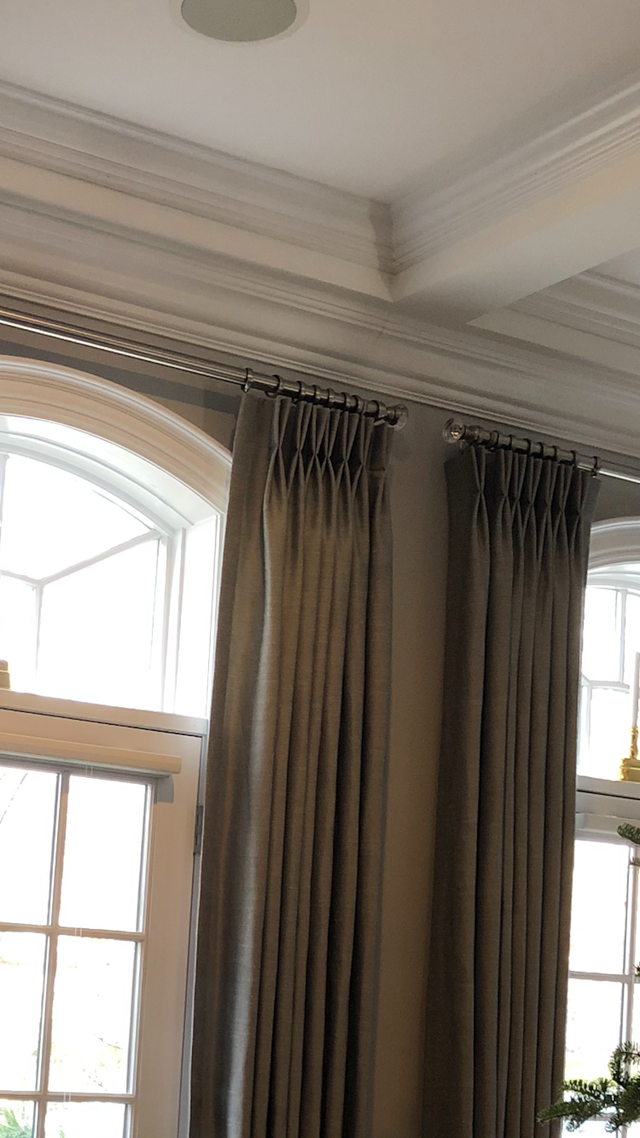 Tall curtains beside arched windows under a white decorative ceiling molding