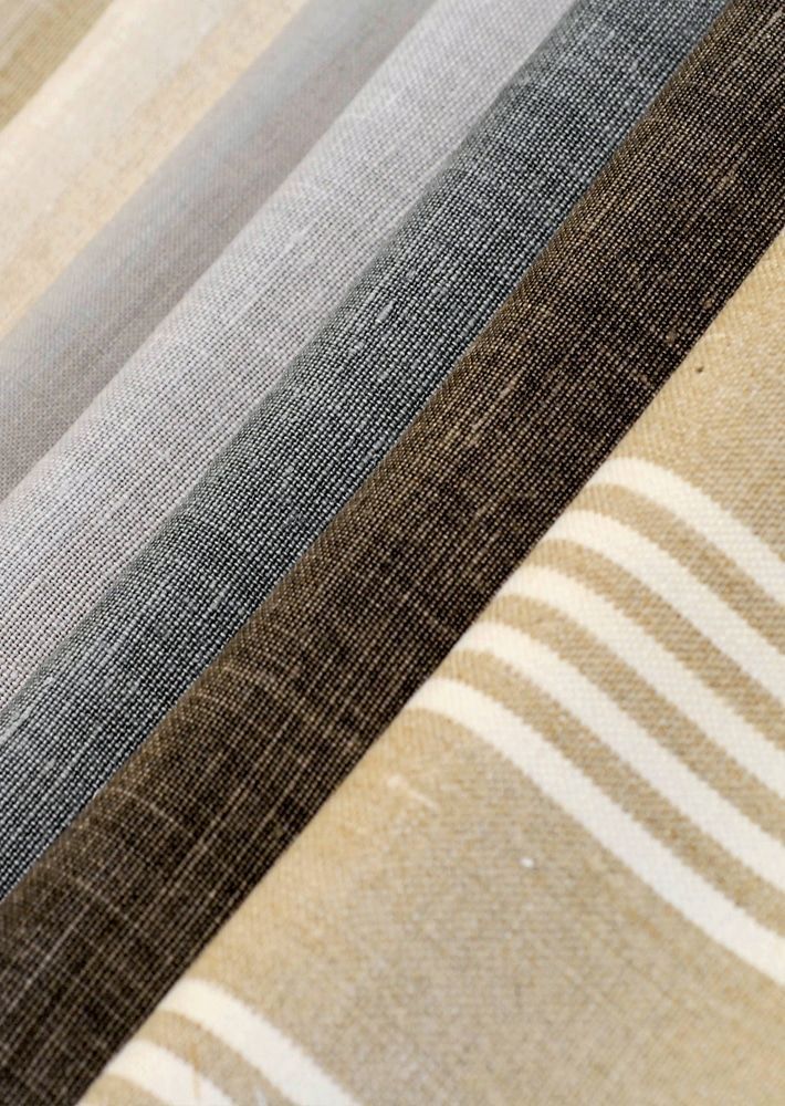 Folded fabric swatches in gray, tan, and striped beige patterns arranged diagonally.