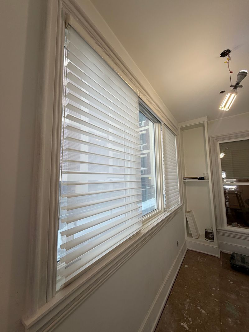 Narrow hallway with white blinds on a window and a ceiling light, showing a home interior.