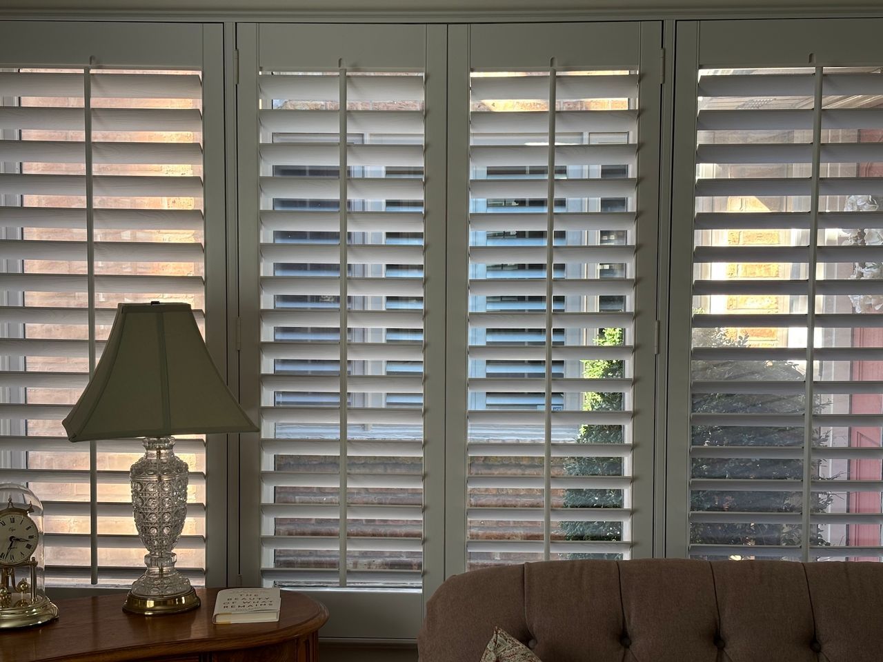 Living room with white plantation shutters, lamp, and gray sofa