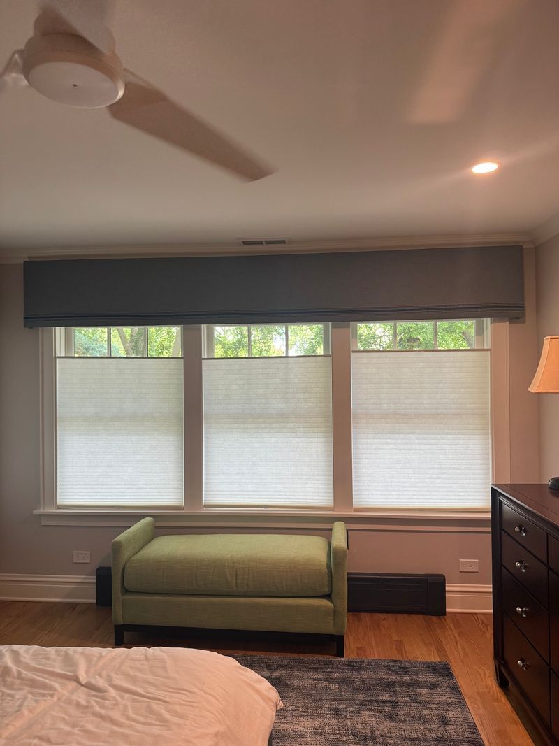 Bedroom with green bench under windows, ceiling fan, and dresser on hardwood floor