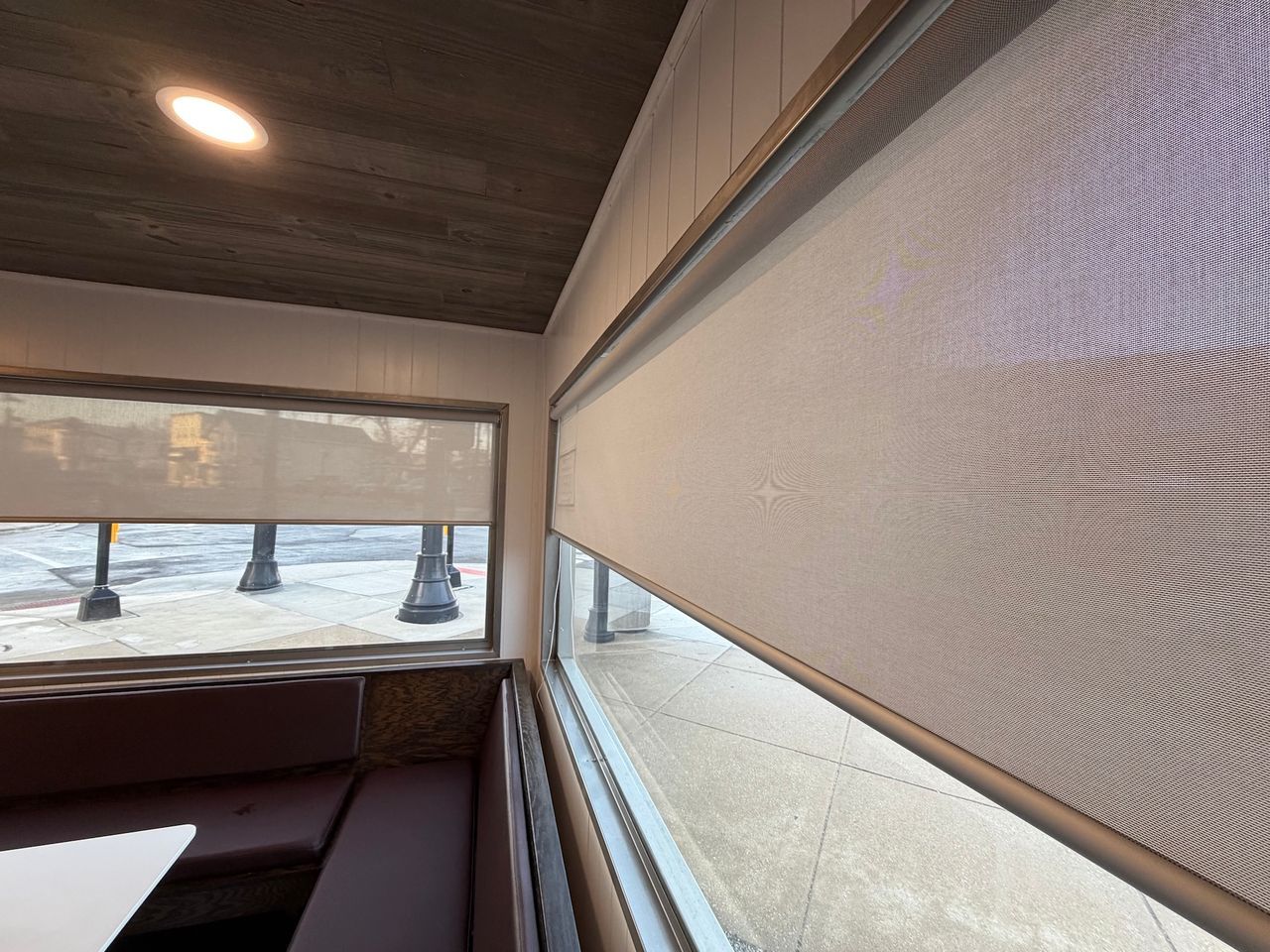 Covered porch with beige roll-down shades, wood ceiling, and snowy ground visible outside.