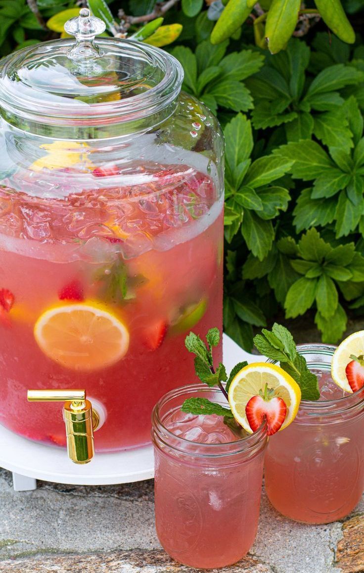 A pitcher of strawberry lemonade and two glasses of strawberry lemonade.