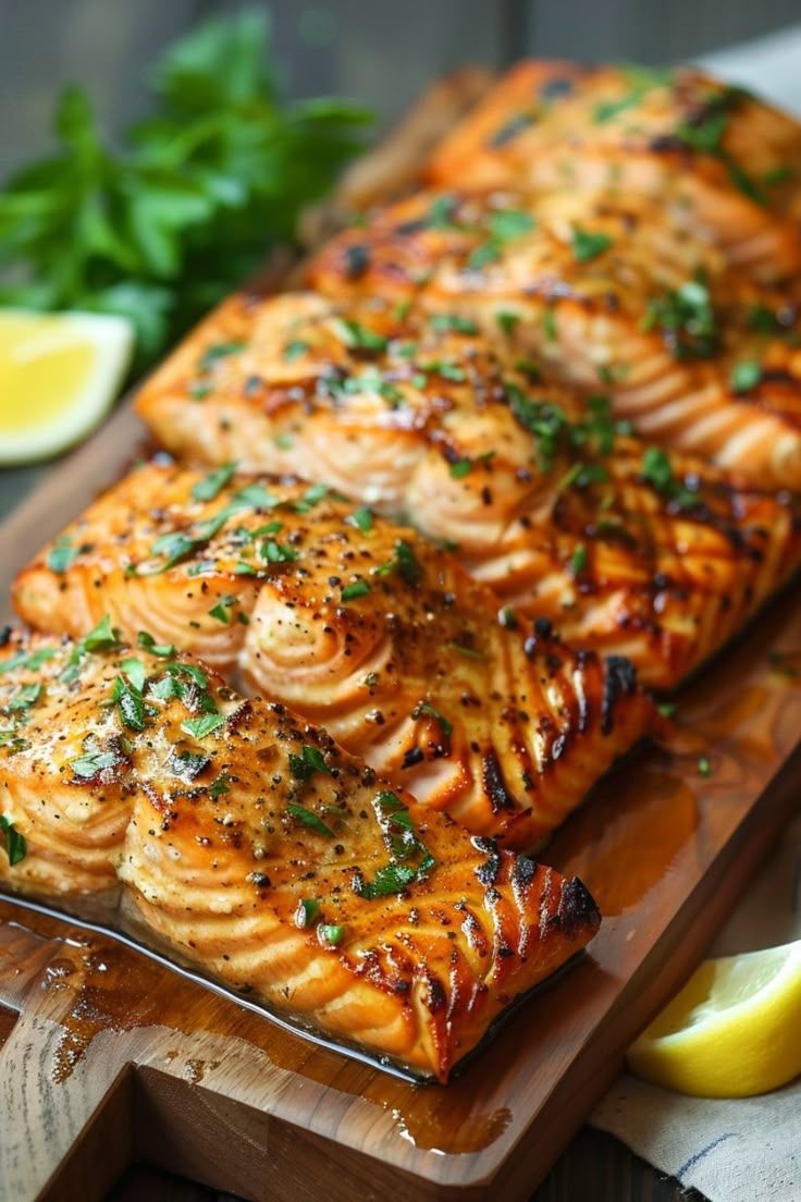 A wooden cutting board topped with grilled salmon and lemon slices.