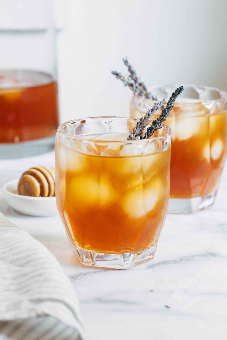 Two glasses of iced tea with lavender and honey on a table.