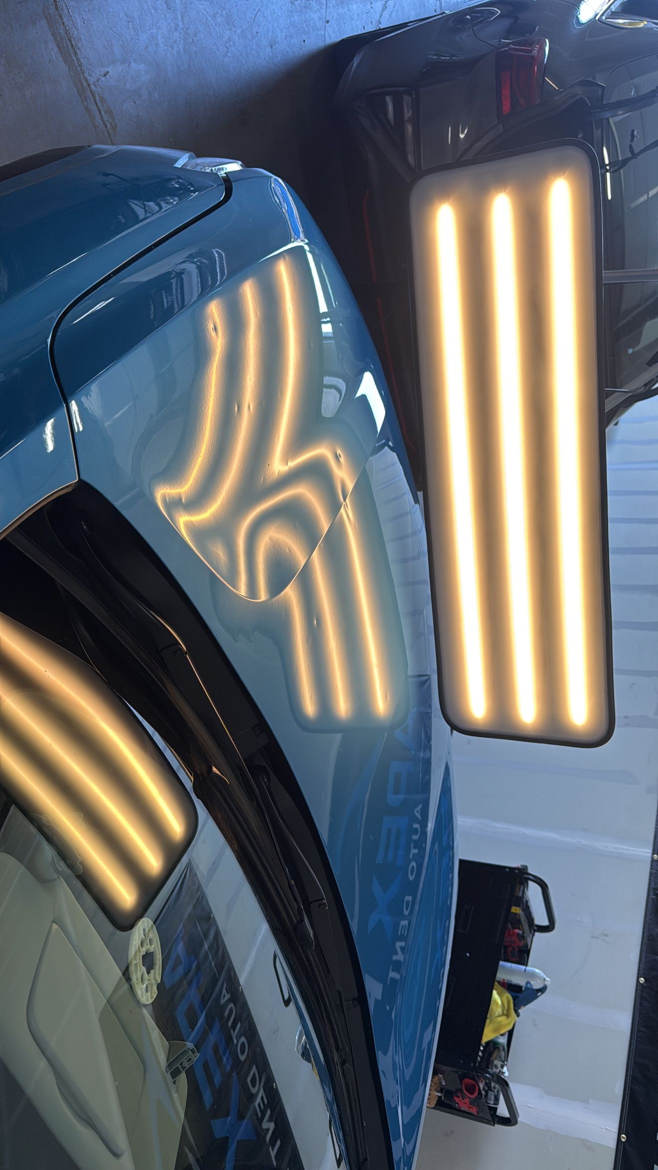 A close-up, top-down view of the hood of a gray Kia vehicle, showing its logo and windshield.