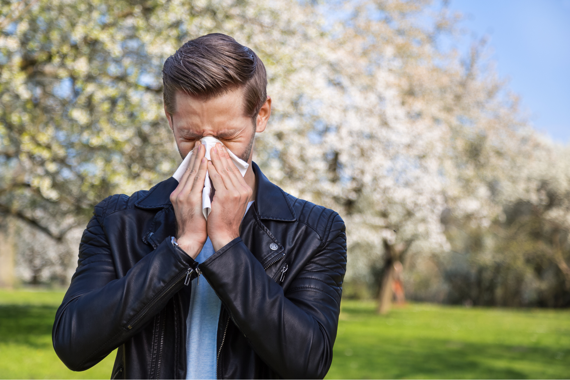 A man with allergies is blowing his nose.