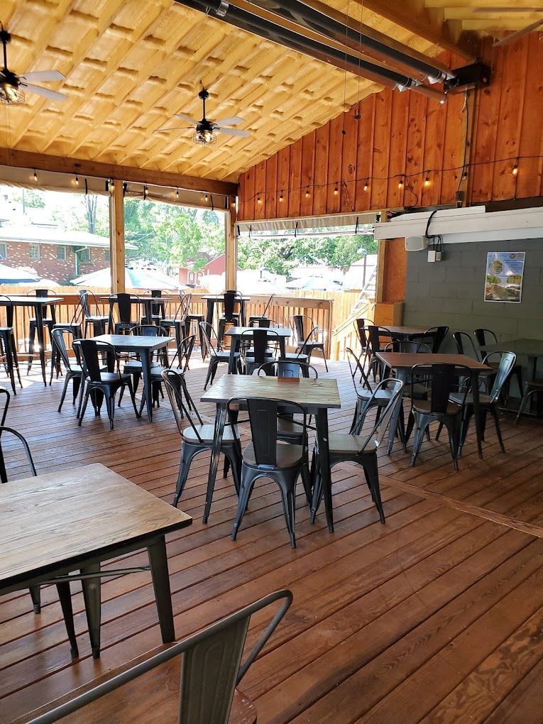 A restaurant with tables and chairs on a wooden deck.