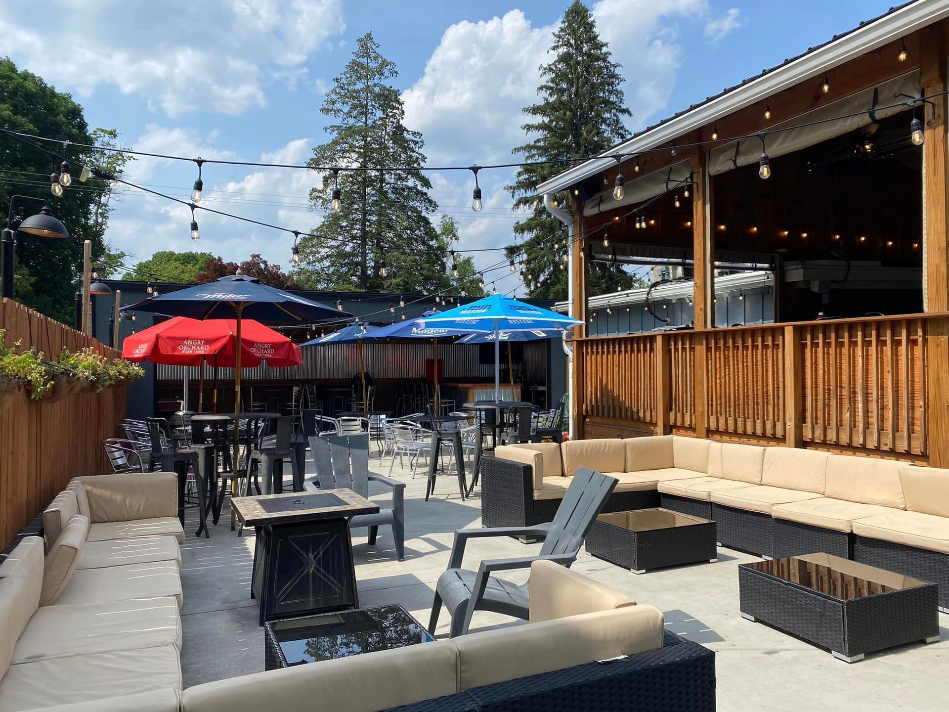 A patio with a lot of furniture and umbrellas at Happy Hour Bar & Grill