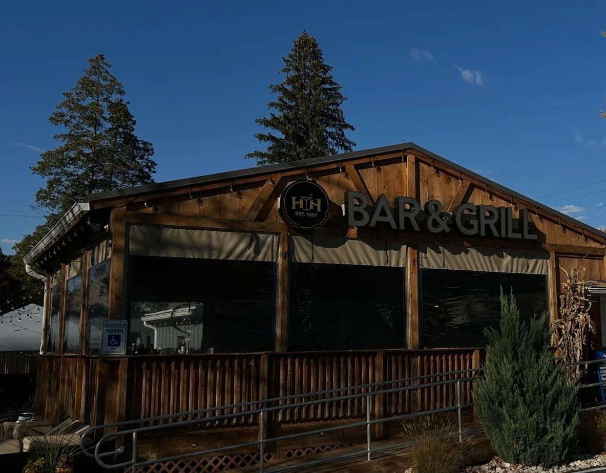 A wooden building with a sign that says Happy Hour Bar & Grill