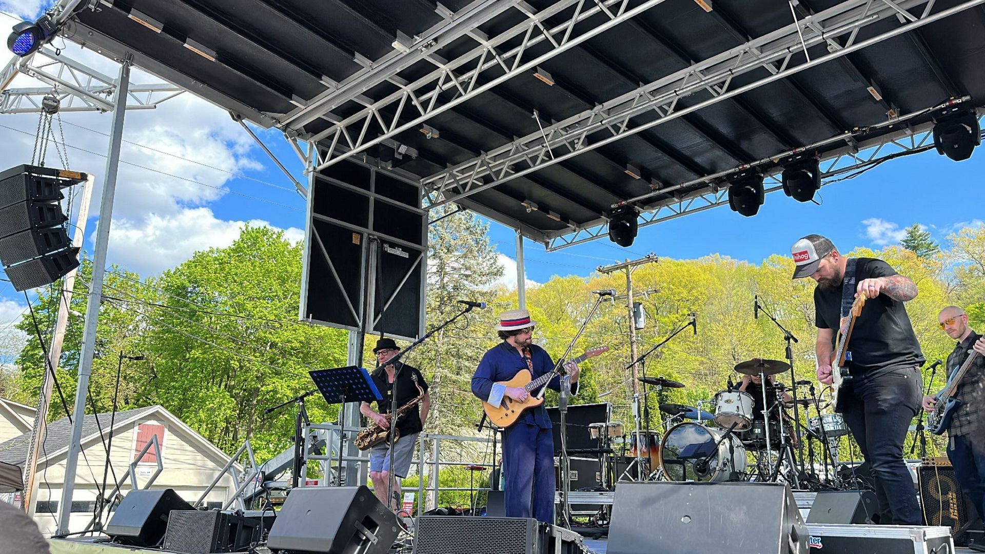 A group of men are playing instruments on a stage at Happy Hour Street Fest