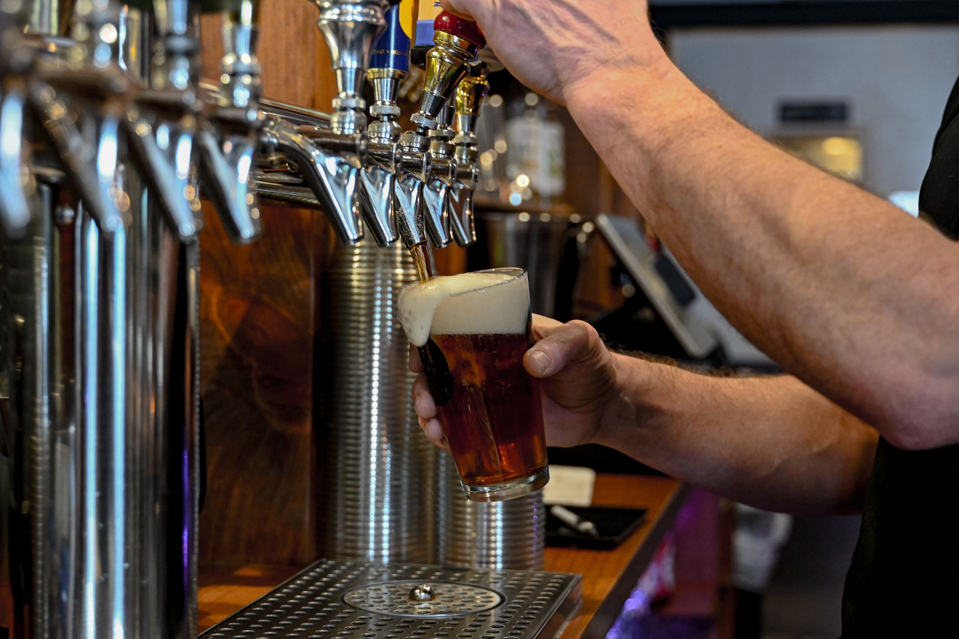 Row of shots on a bar, lit with purple and blue lights, near a tap.