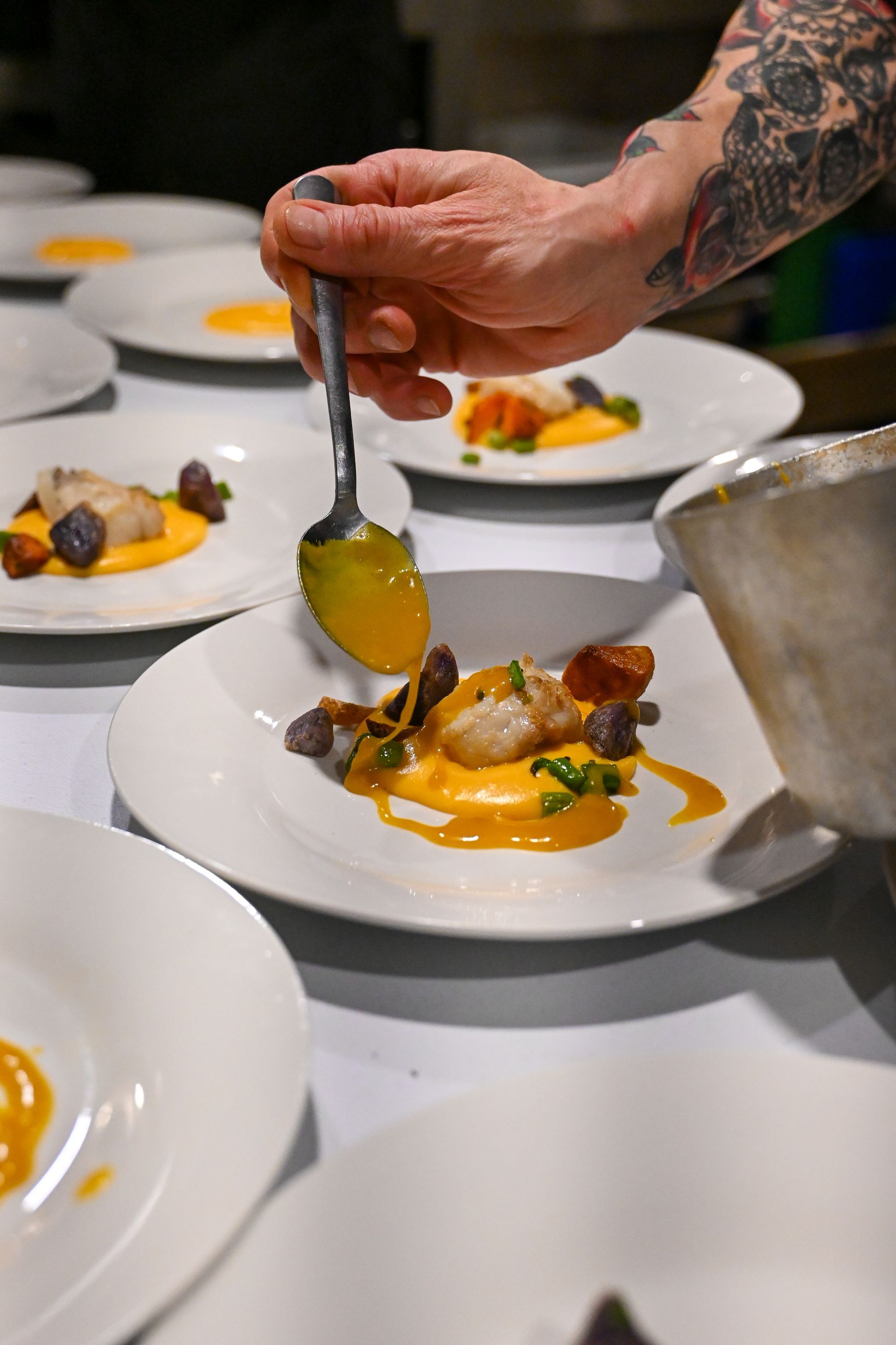 A person is holding a spoon over a plate of food.