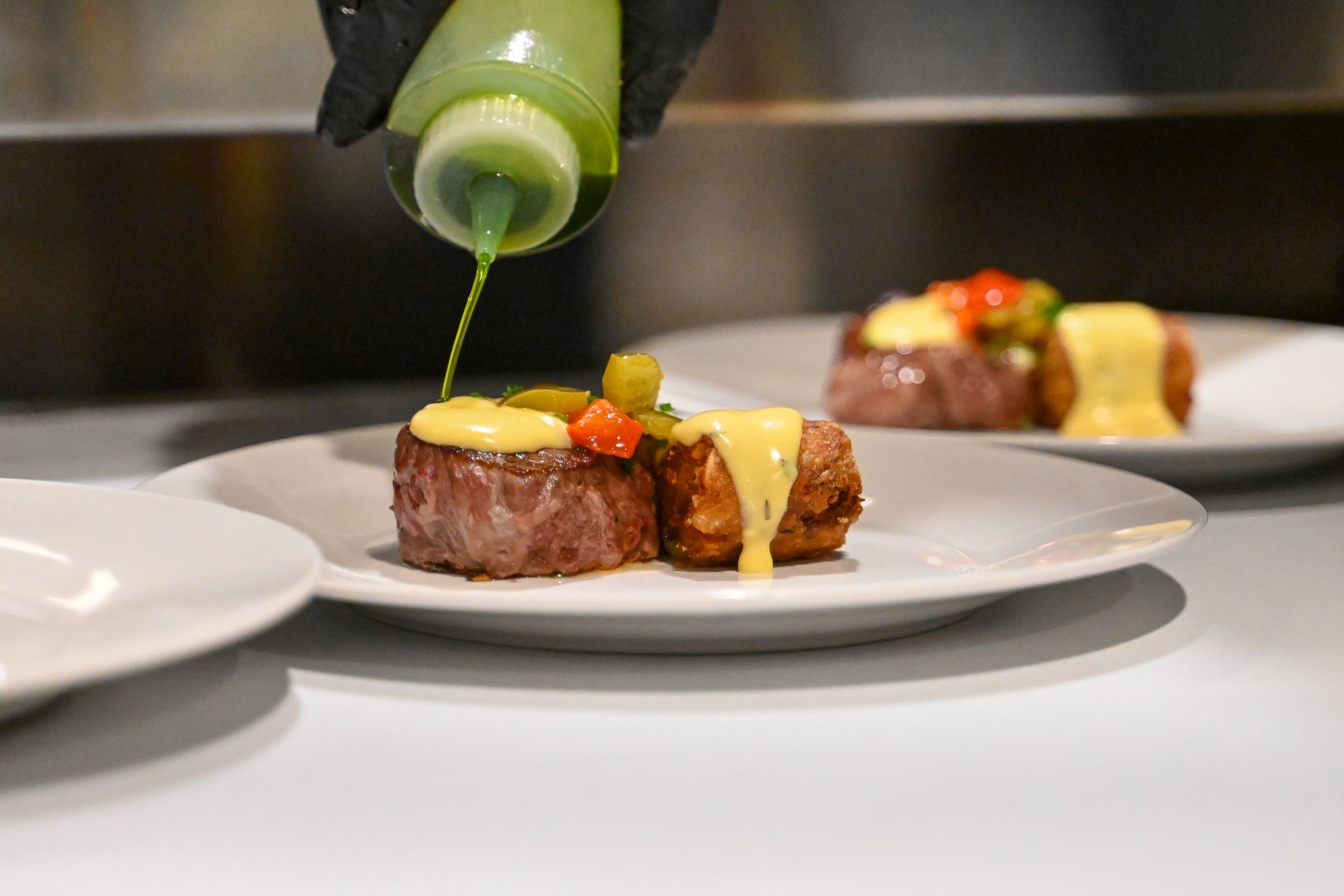 A person is pouring sauce on a plate of food.