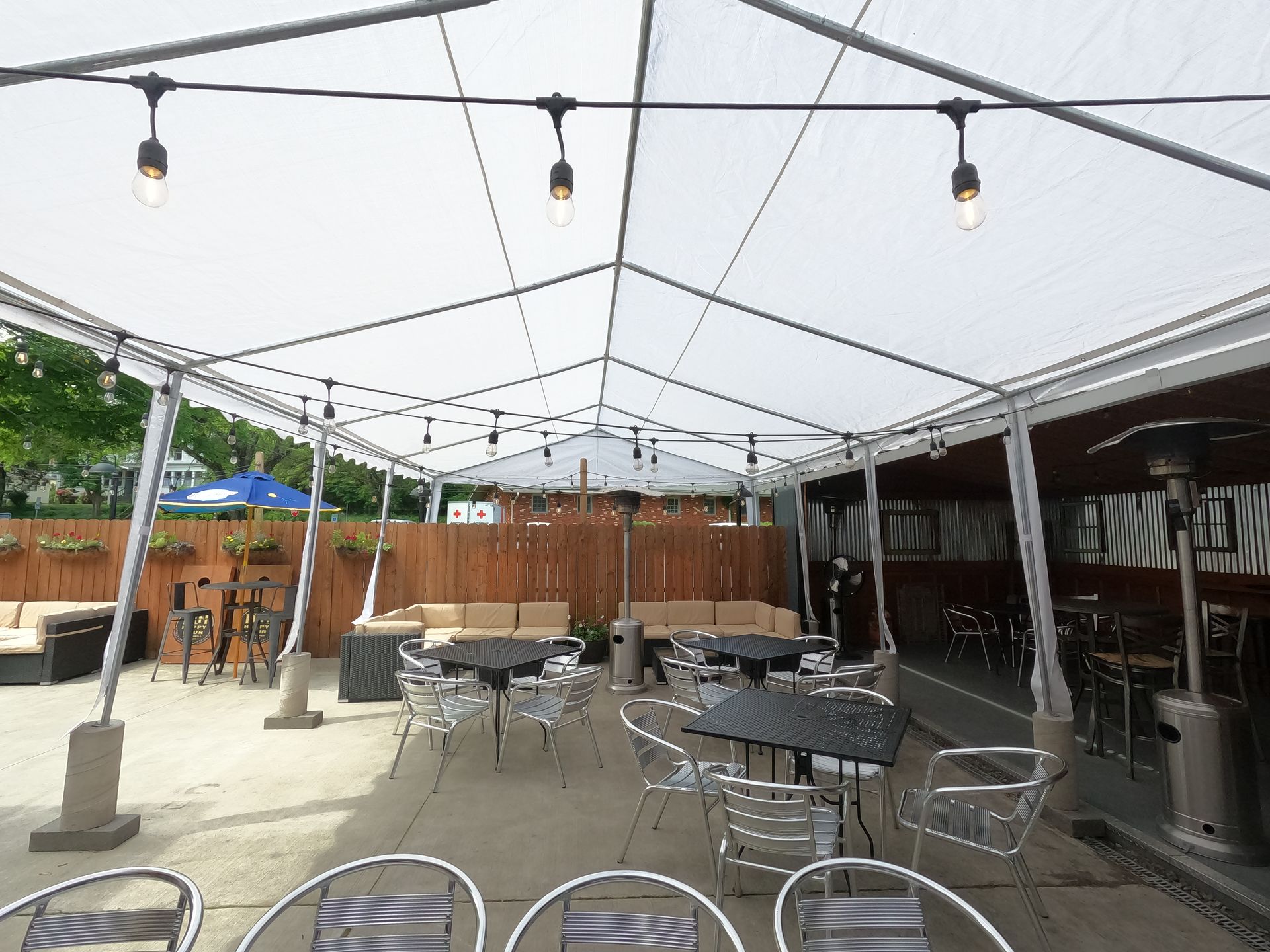 A patio with tables and chairs under a tent at Happy Hour Bar & Grill