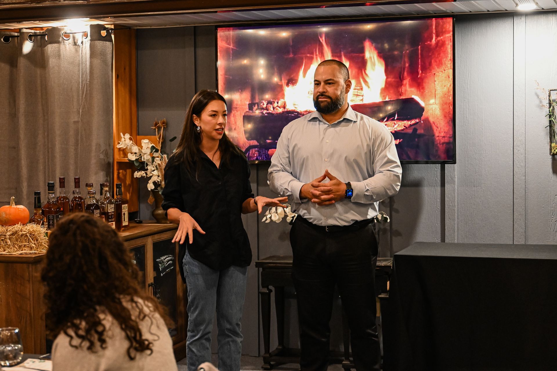 A man and a woman are standing in front of a fireplace.