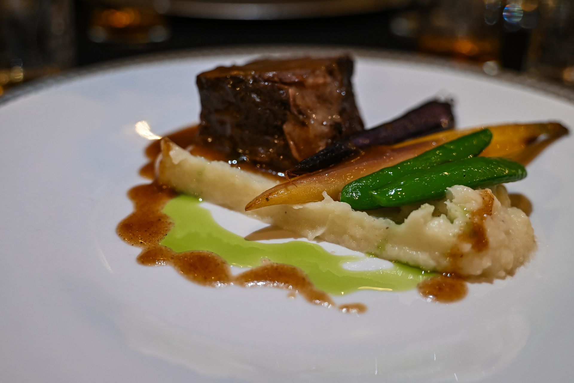 A close up of a plate of food with meat and vegetables on a table.