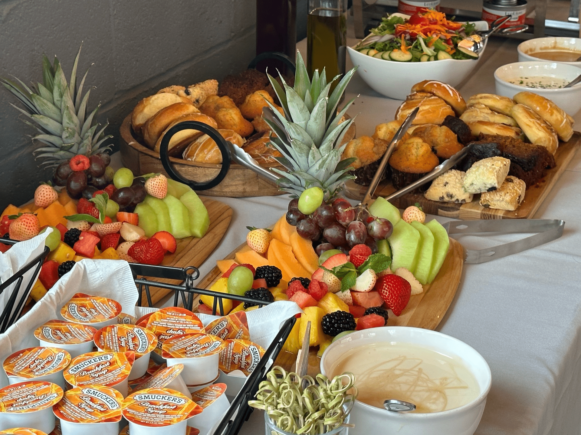 A buffet table with a variety of food including fruit and bread at Happy Hour Bar & Grill
