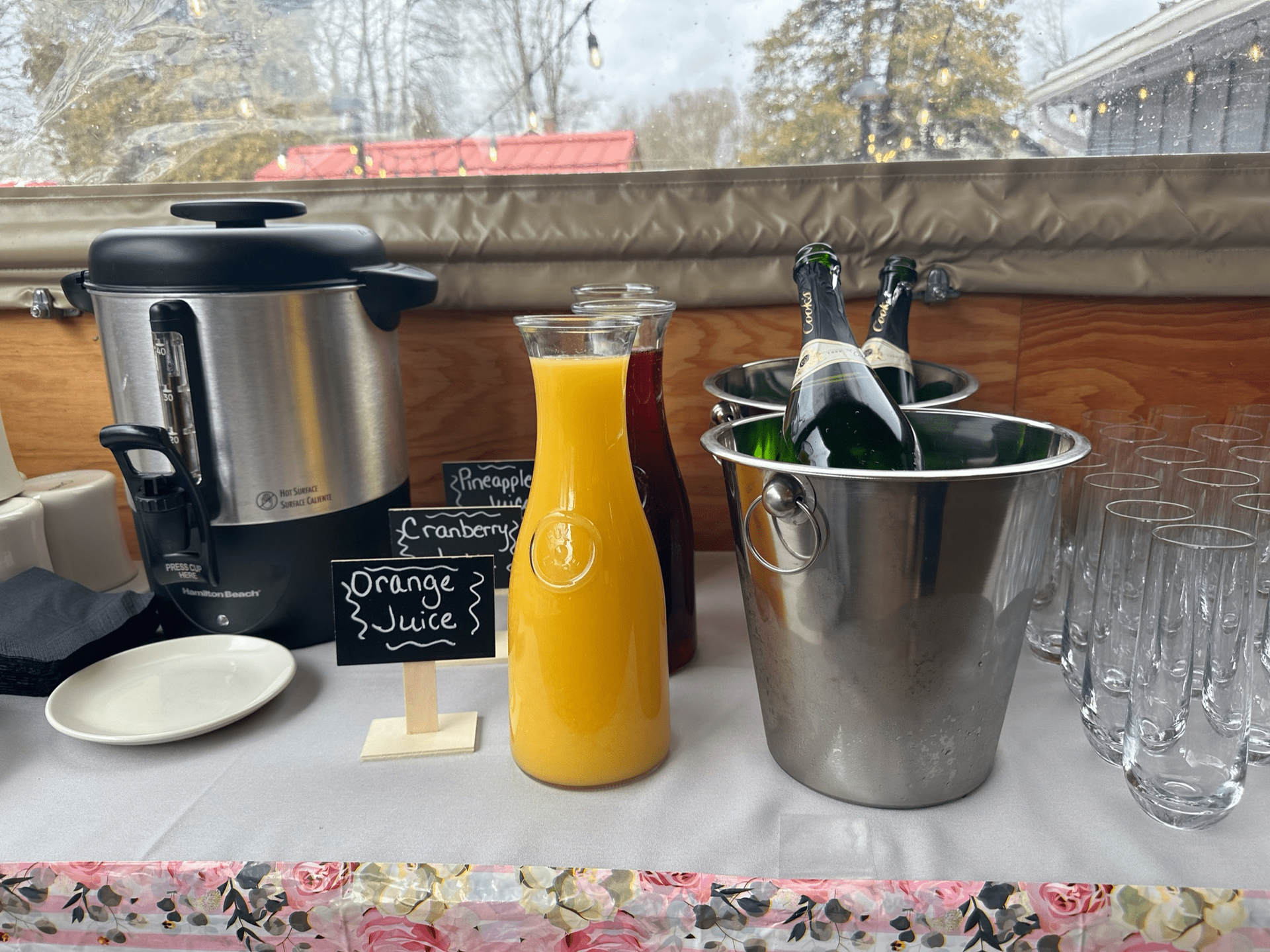 A table with bottles of wine , juice , and glasses on it at Happy Hour Bar & Grill.