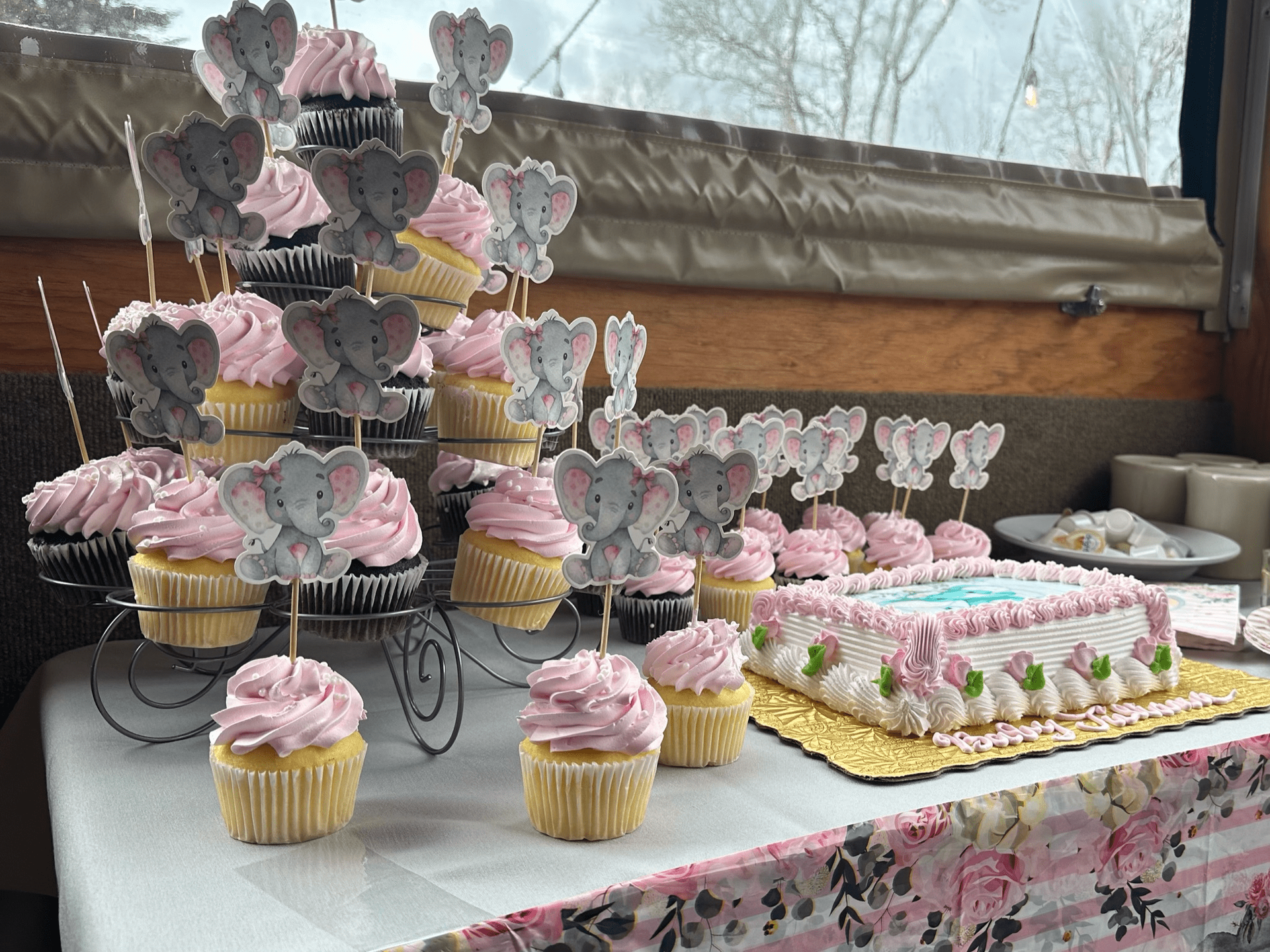 A table topped with cupcakes and a cake for a baby shower at Happy Hour Bar & Grill