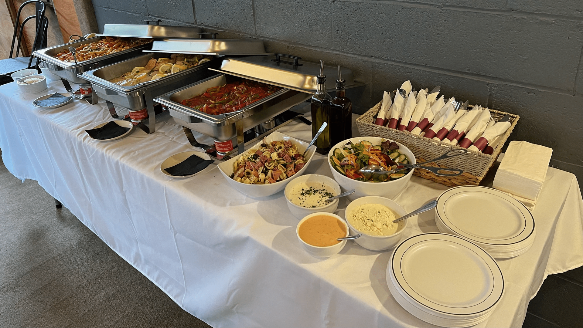 A long table topped with bowls of food and plates at Happy Hour Bar & Grill