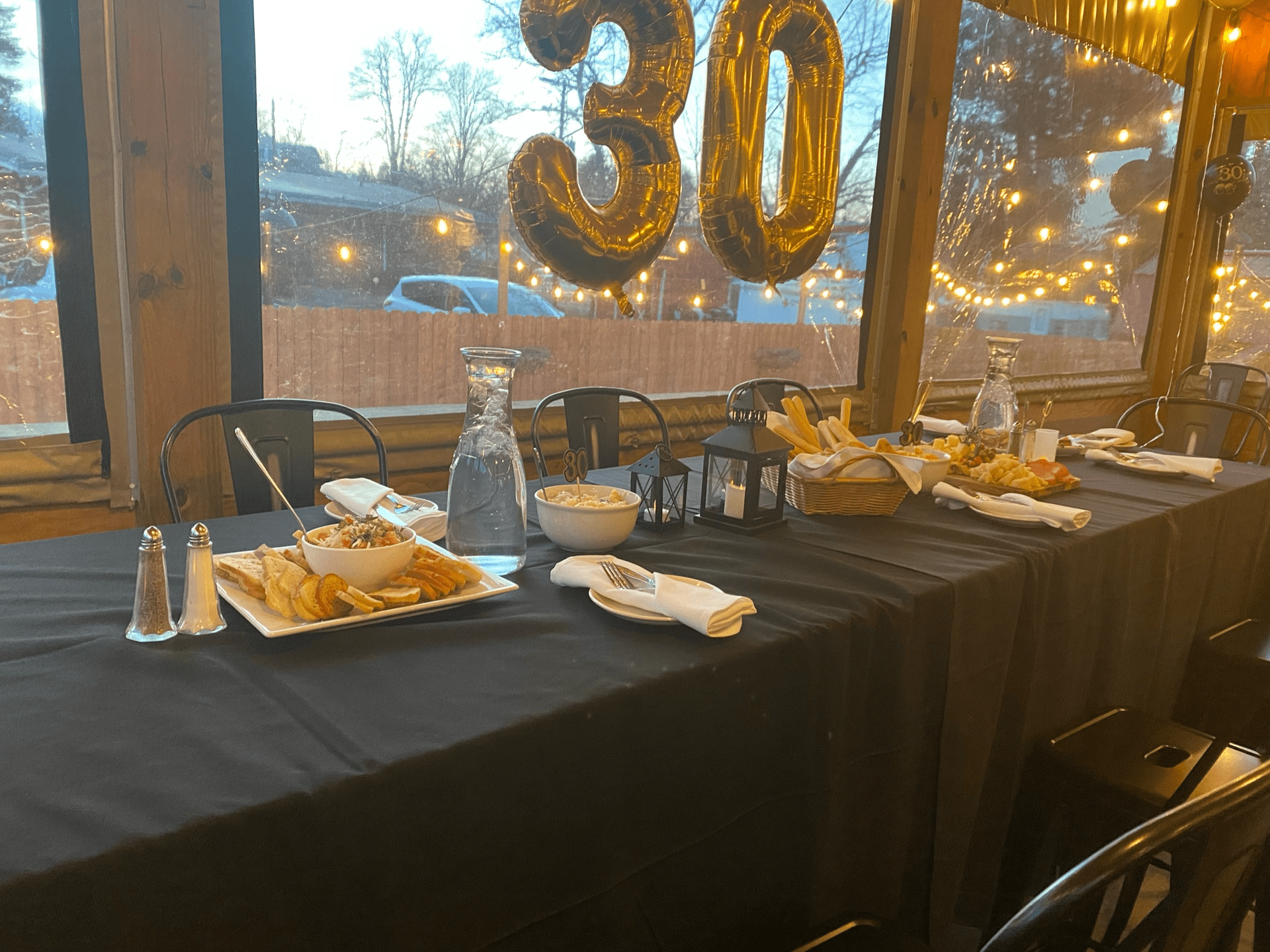 A long table with plates of food and balloons on it at Happy Hour Bar & Grill