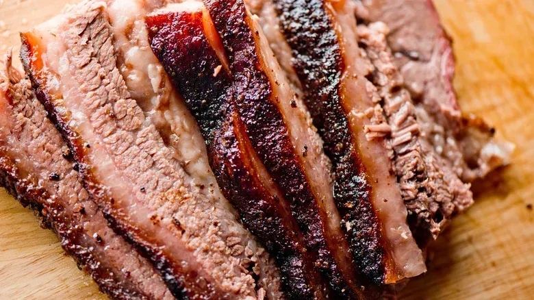 A close up of a piece of meat on a wooden cutting board. A close up of a piece of meat on a wooden cutting board.