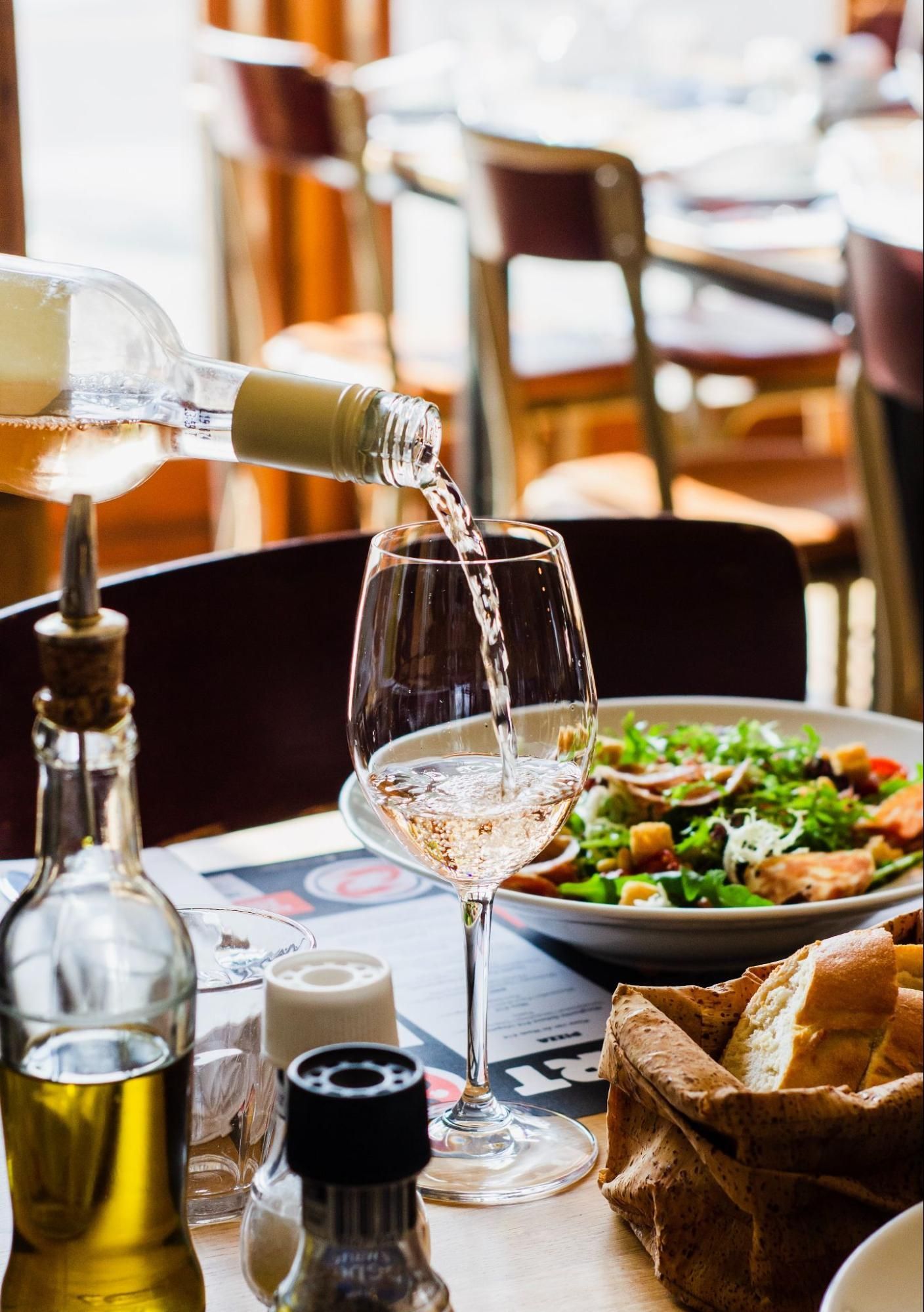 A bottle of wine is being poured into a glass on a table.