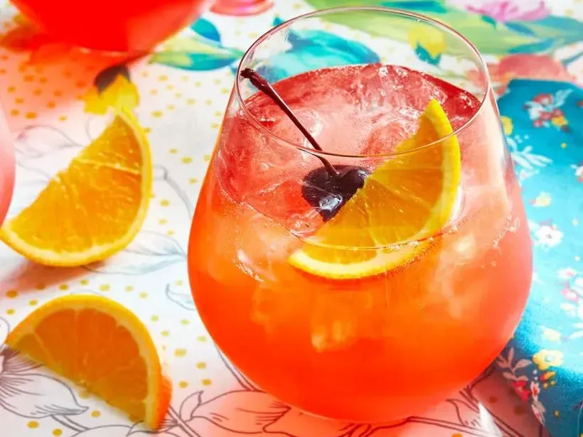 A close up of a glass of orange juice with ice and a cherry on top. A close up of a glass of orange juice with ice and a cherry on top.