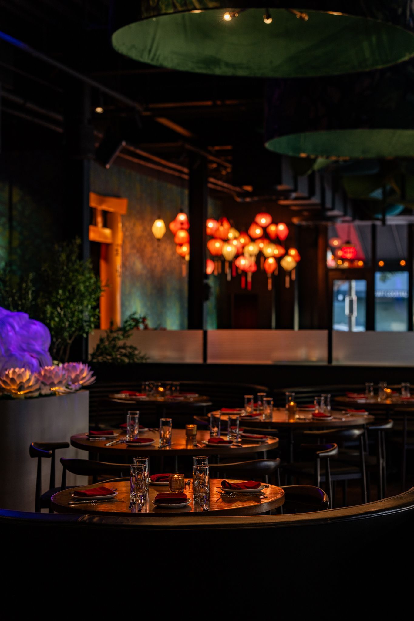 A restaurant filled with tables and chairs and lanterns hanging from the ceiling.
