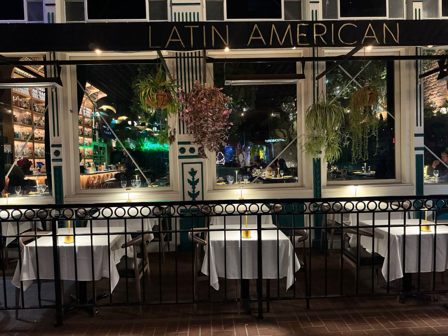 A restaurant with tables and chairs and a green wall.