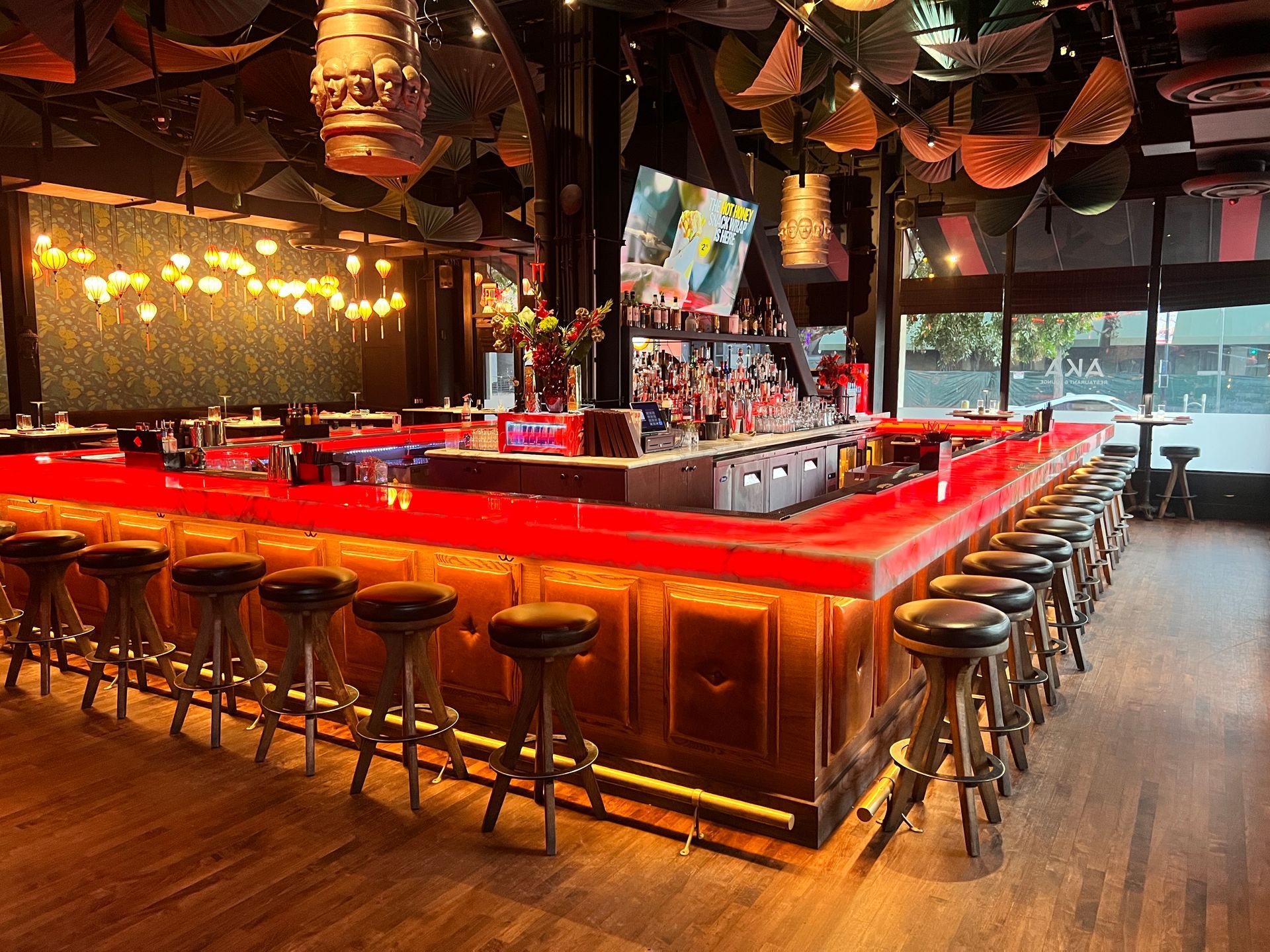 A restaurant with a long red bar and stools.