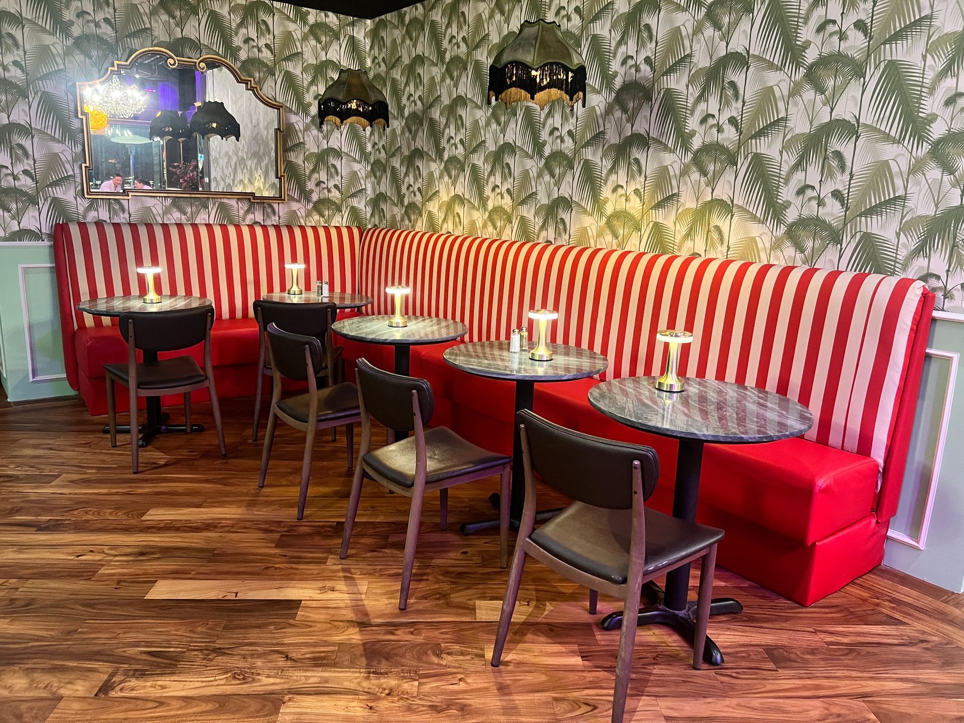 A restaurant with tables and chairs and a striped couch.