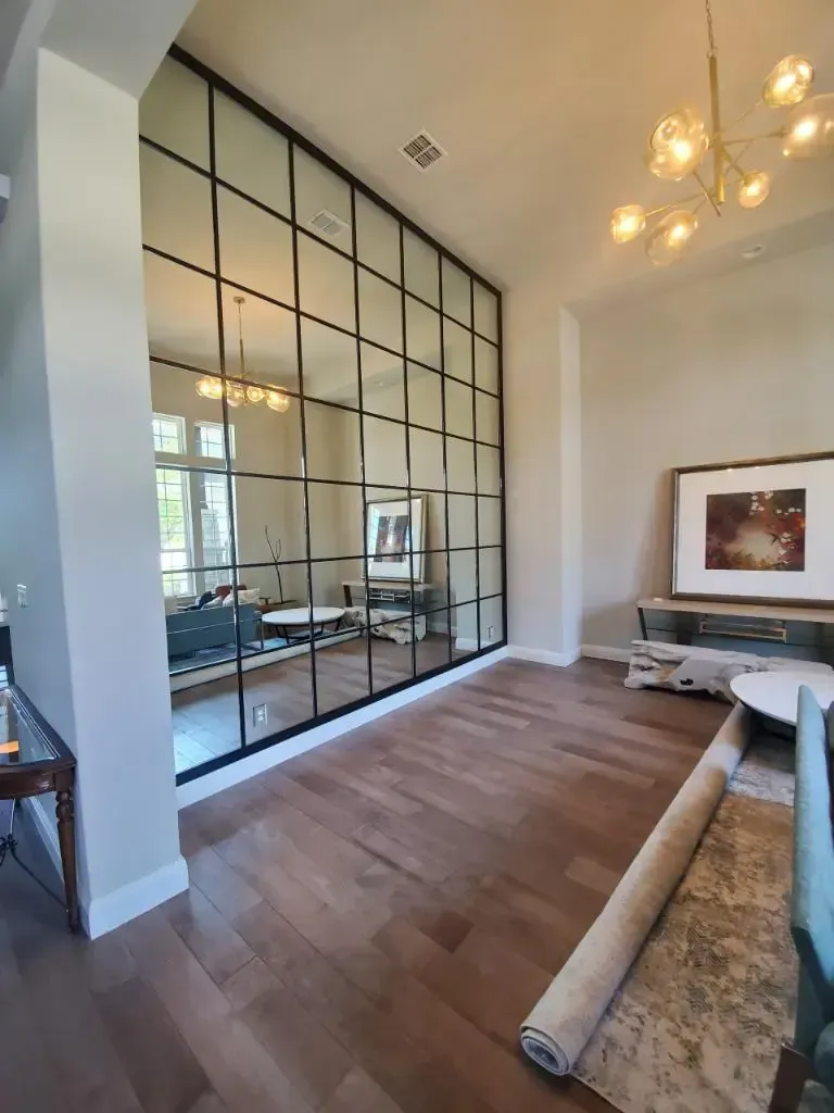 A living room with a large mirror wall and a rug on the floor.