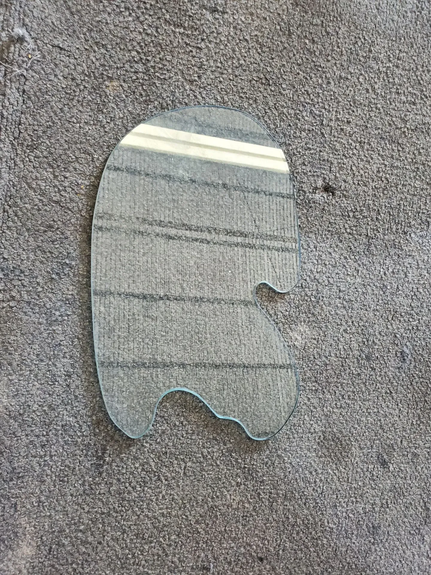 A piece of glass is sitting on a concrete surface.