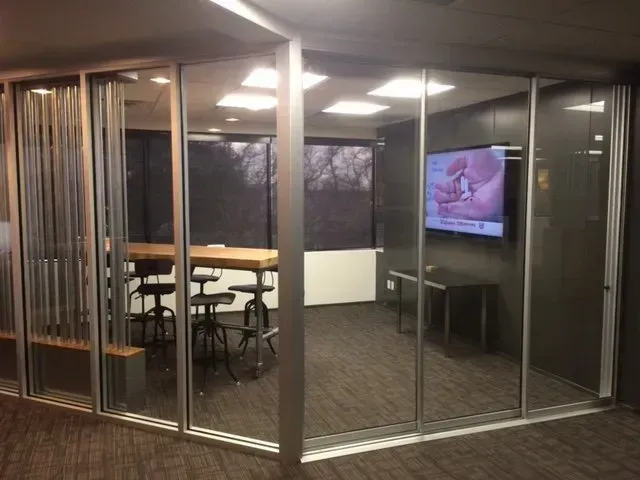 A conference room with a table and chairs and a flat screen tv on the wall.