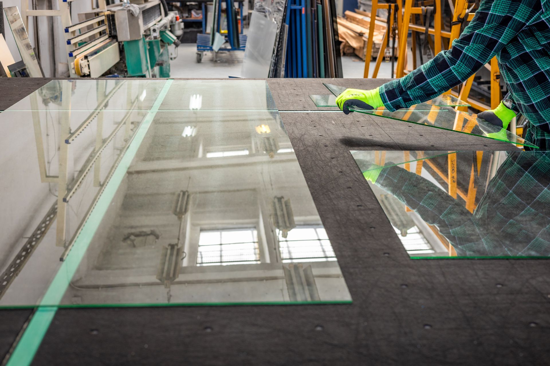A man is cutting a piece of glass at Alamo Glass in Austin, TX.