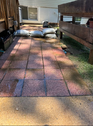 A brick walkway with bags of sand on it next to a wooden bench.
