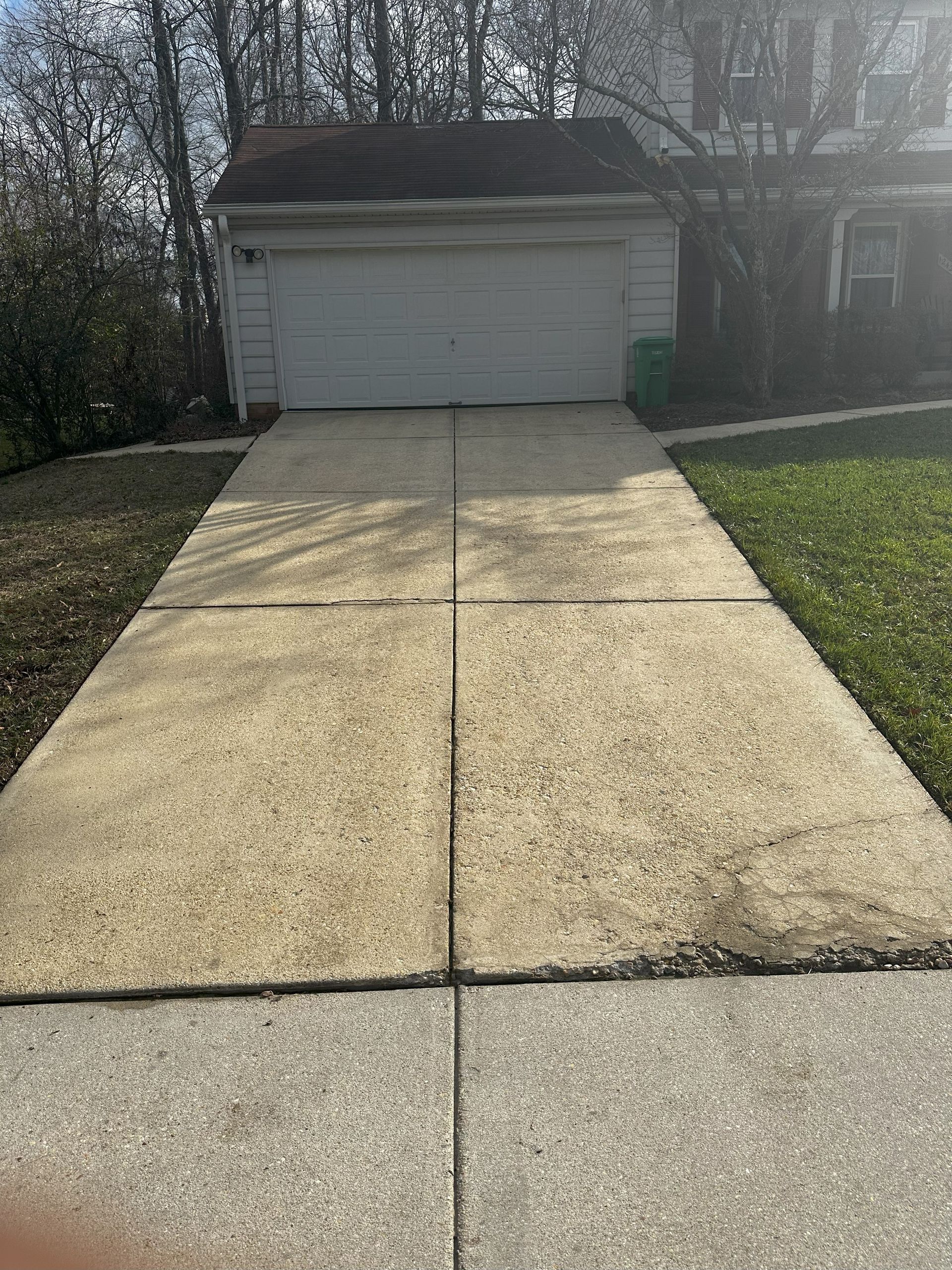 A concrete driveway leading to a garage next to a house.