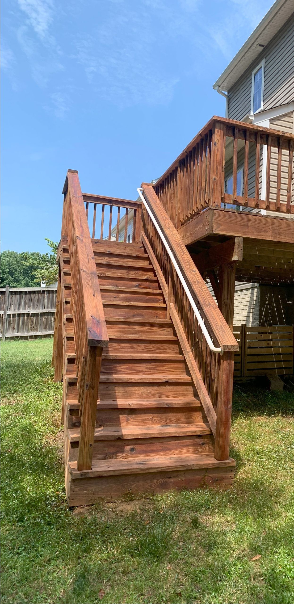 A wooden deck with stairs leading up to it and a house in the background.