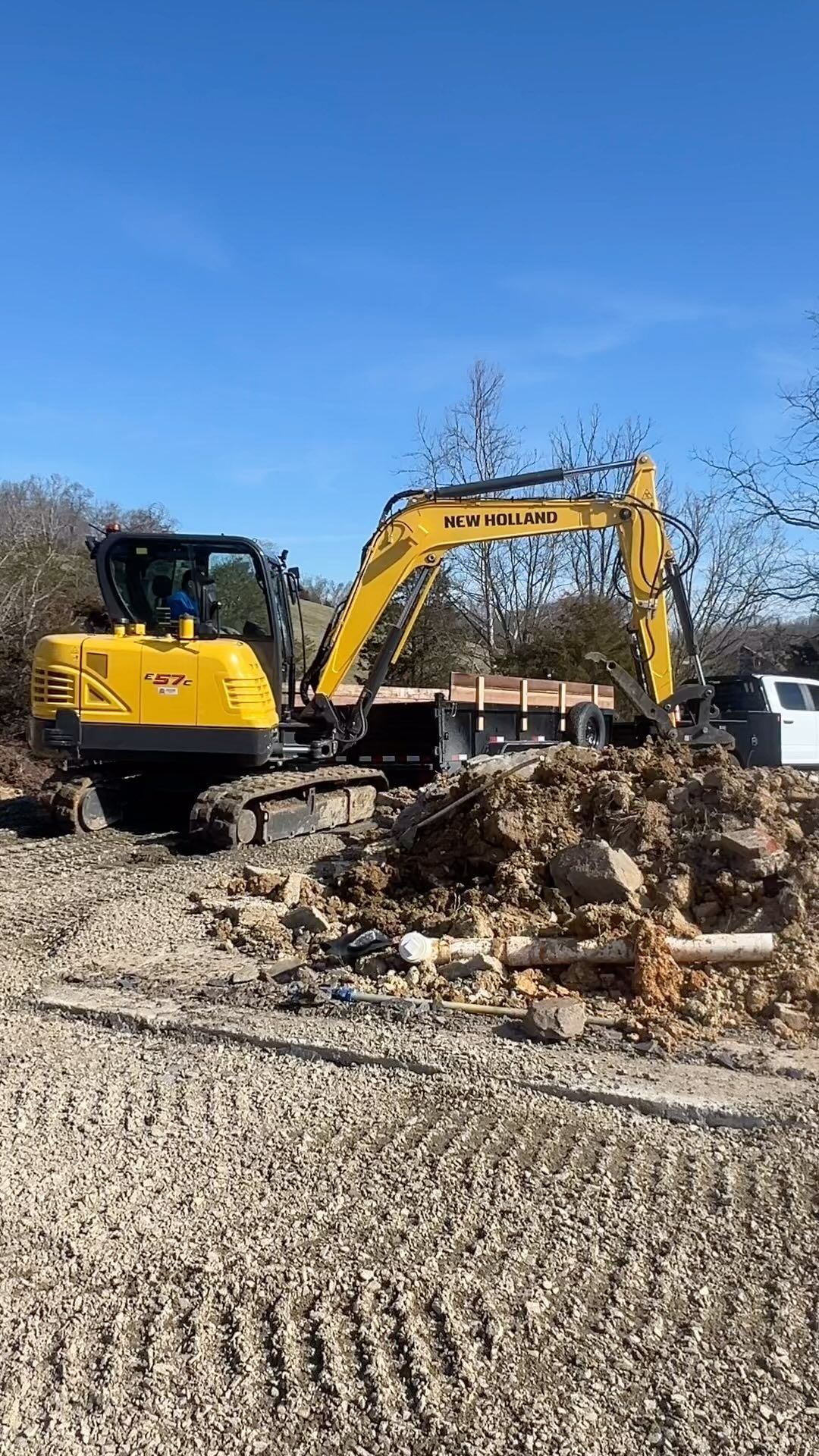 Yellow excavator on dirt, digging. Blue sky background.